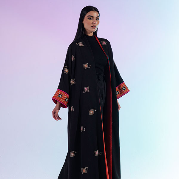 A hand-embroidered wool abaya with bright colors and patterns inspired by the Hijaz region