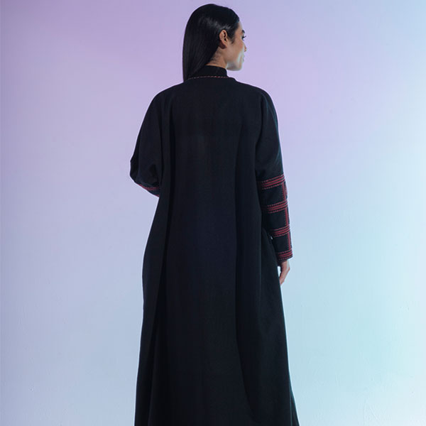 A hand-embroidered wool abaya with red threads and patterns inspired by the Najd region