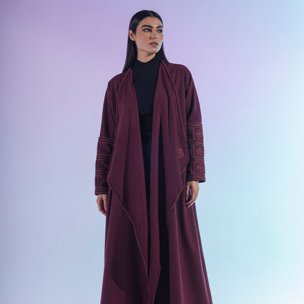 A hand-embroidered wool abaya with red threads and patterns inspired by the Najd region