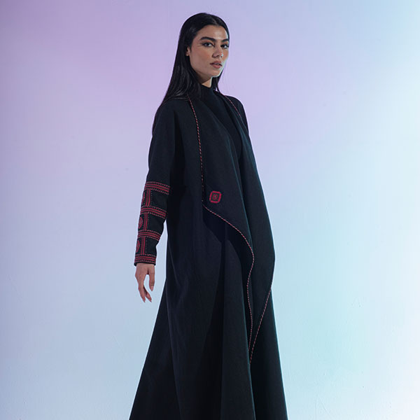 A hand-embroidered wool abaya with red threads and patterns inspired by the Najd region